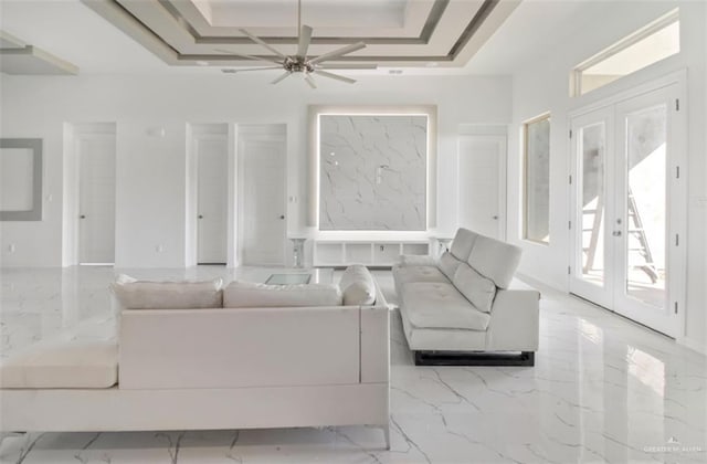 unfurnished living room with ceiling fan, a raised ceiling, and french doors