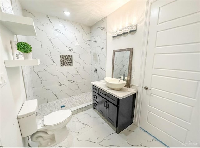 bathroom with toilet, vanity, and tiled shower