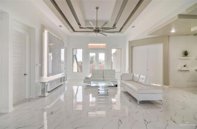 interior space with ceiling fan, a raised ceiling, and french doors