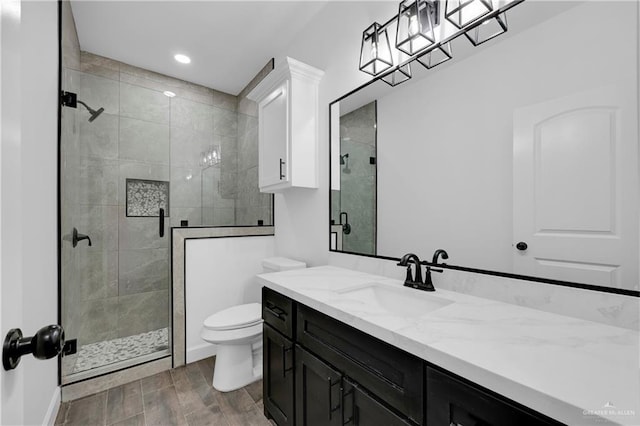 bathroom featuring toilet, vanity, an enclosed shower, and hardwood / wood-style flooring