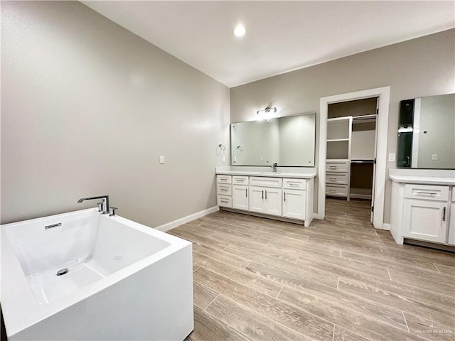 bathroom with a tub to relax in, vanity, and hardwood / wood-style flooring