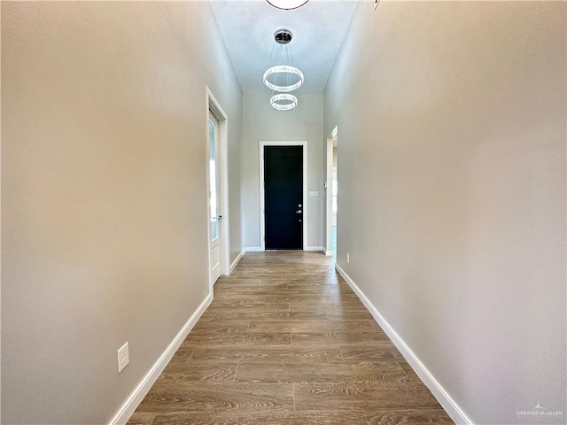 corridor featuring a chandelier and wood-type flooring