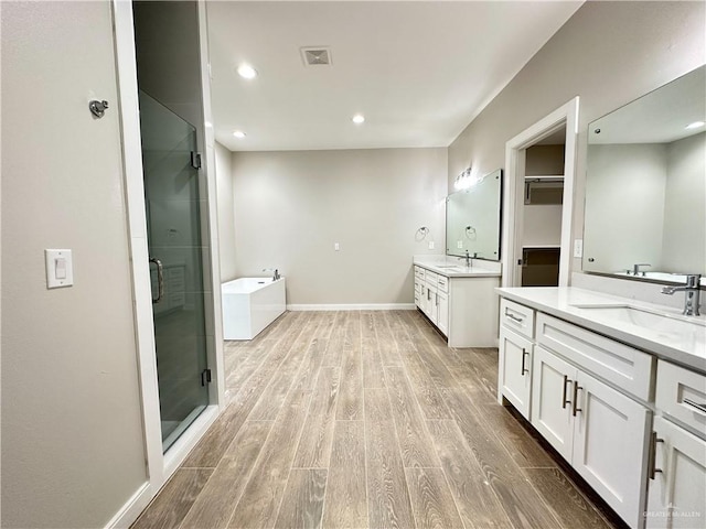 bathroom with hardwood / wood-style floors, vanity, and independent shower and bath