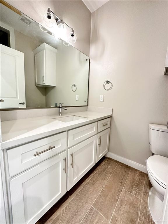 bathroom with vanity, hardwood / wood-style flooring, and toilet