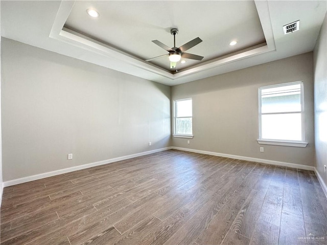 unfurnished room featuring hardwood / wood-style flooring, ceiling fan, and a raised ceiling