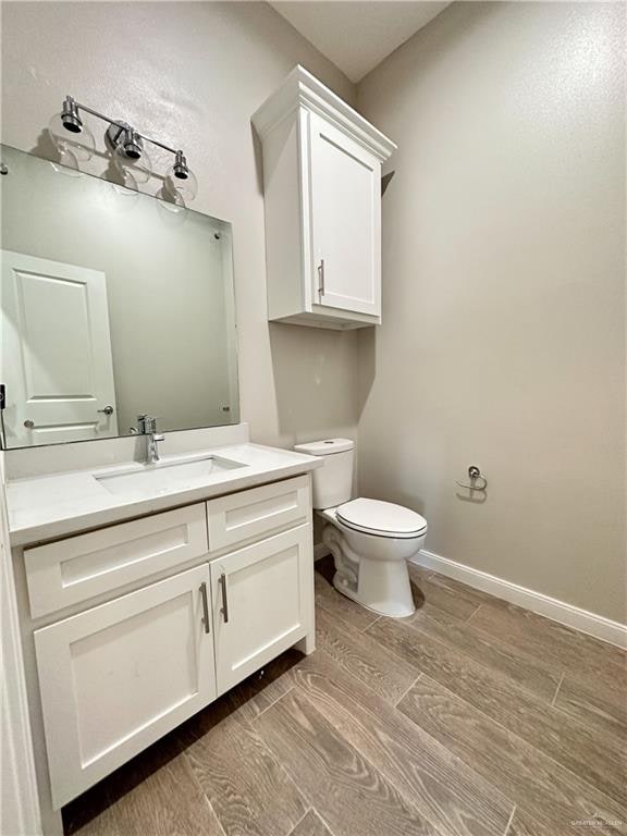 bathroom with hardwood / wood-style floors, vanity, and toilet