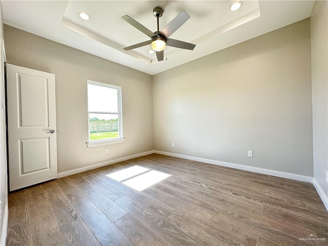 empty room featuring a tray ceiling, ceiling fan, and hardwood / wood-style floors