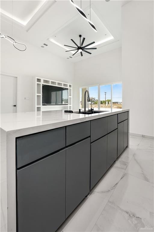 kitchen featuring a tray ceiling, gray cabinetry, ceiling fan, and sink