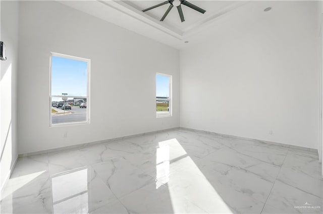 spare room featuring a raised ceiling and ceiling fan