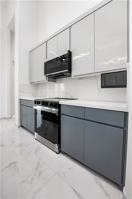 kitchen featuring gray cabinetry, light stone counters, and stainless steel range