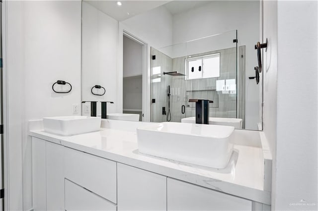 bathroom featuring a shower with door and vanity