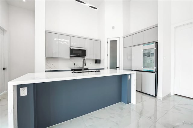 4713 S Brazos Rd S, Edinburg, TX 78542 - kitchen featuring appliances with stainless steel finishes, light marble finish flooring, a high ceiling, modern cabinets, and a large island with sink