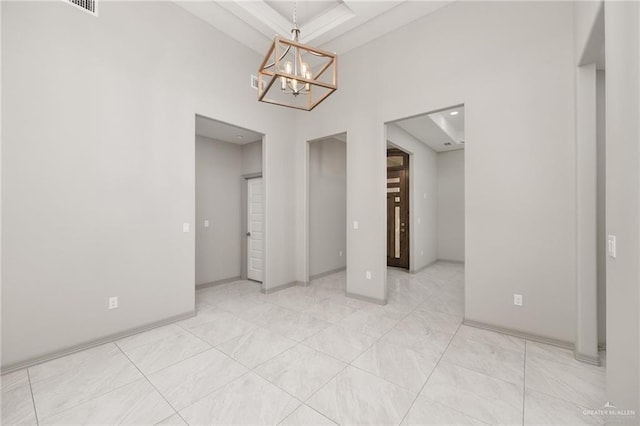 unfurnished dining area featuring a chandelier, a raised ceiling, and baseboards