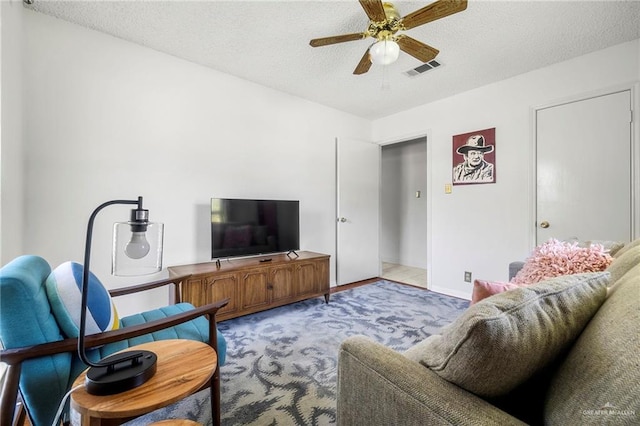 carpeted living room featuring ceiling fan and a textured ceiling