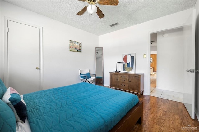 bedroom featuring ceiling fan, hardwood / wood-style floors, and a textured ceiling