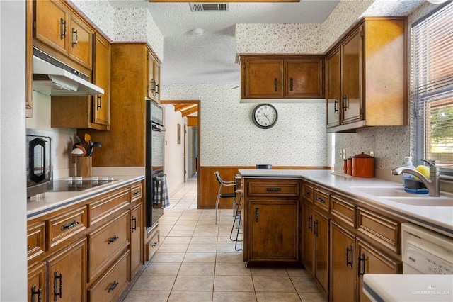 kitchen with sink, light tile patterned floors, a textured ceiling, and black appliances