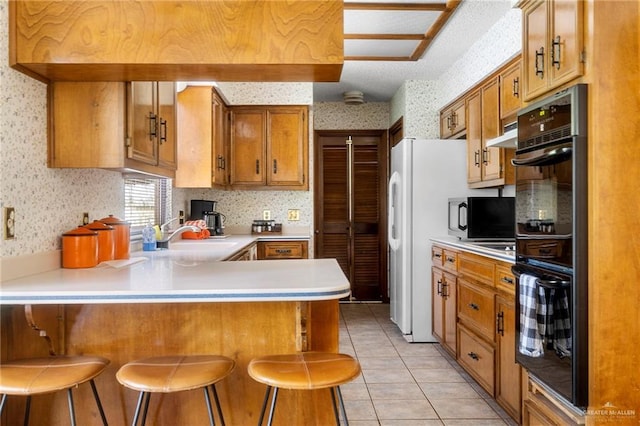 kitchen with kitchen peninsula, sink, a breakfast bar area, and black appliances