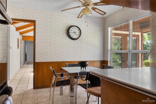 dining area featuring ceiling fan, vaulted ceiling, light tile patterned floors, and a textured ceiling