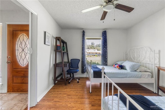 bedroom featuring ceiling fan, wood-type flooring, and a textured ceiling