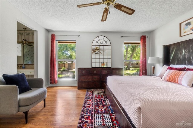 bedroom featuring multiple windows, ceiling fan, a textured ceiling, and light wood-type flooring