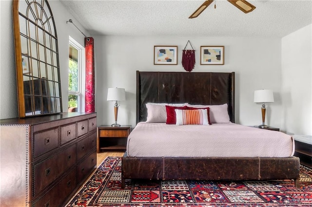 bedroom featuring ceiling fan, light hardwood / wood-style flooring, and a textured ceiling