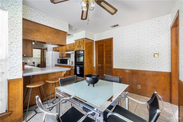 dining room featuring ceiling fan, washing machine and dryer, a textured ceiling, and light tile patterned floors