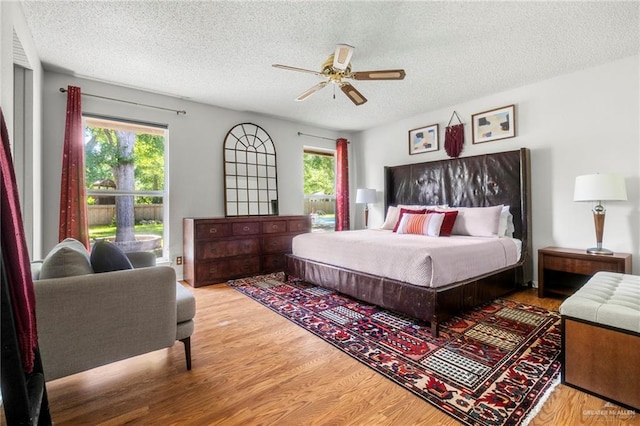 bedroom featuring ceiling fan, a textured ceiling, and light wood-type flooring