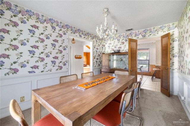 carpeted dining room featuring an inviting chandelier and a textured ceiling