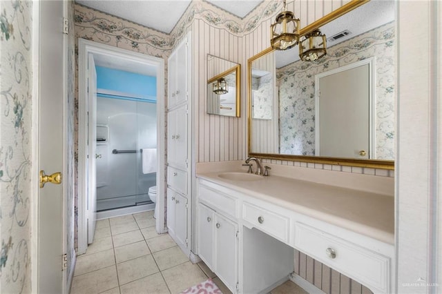 bathroom with vanity, toilet, a shower with shower door, and tile patterned flooring