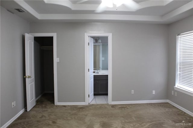 unfurnished bedroom featuring baseboards, a sink, visible vents, and carpet
