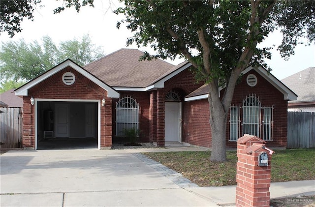 ranch-style home featuring concrete driveway, fence, a garage, brick siding, and roof with shingles