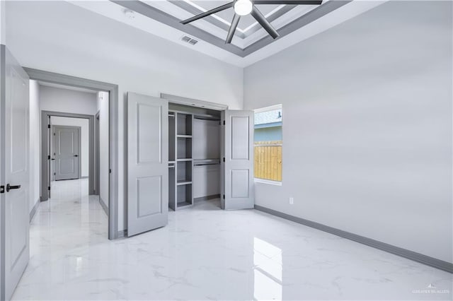 unfurnished bedroom featuring a towering ceiling, marble finish floor, a closet, and baseboards