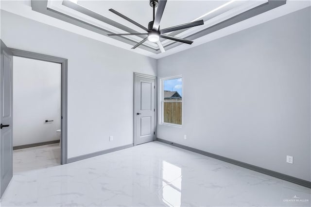 unfurnished bedroom with baseboards, a tray ceiling, ensuite bathroom, and marble finish floor