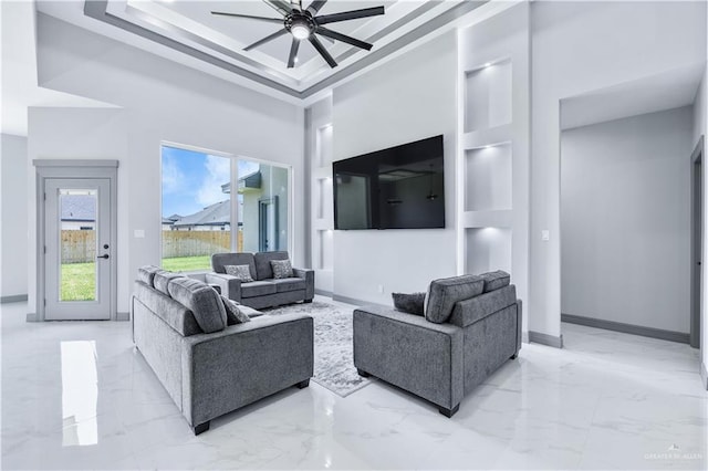 living room featuring a ceiling fan, a high ceiling, marble finish floor, and baseboards