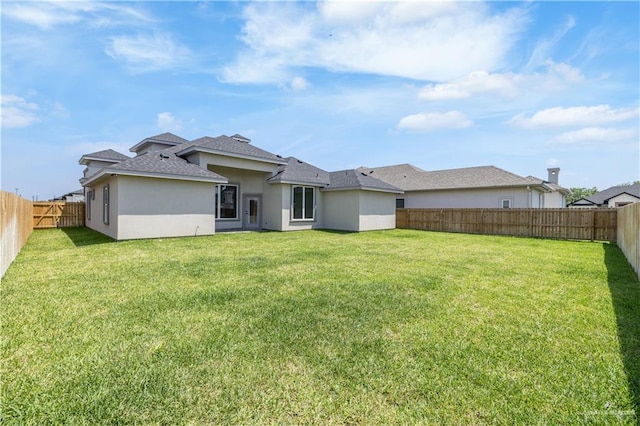 back of house featuring a yard, stucco siding, and a fenced backyard