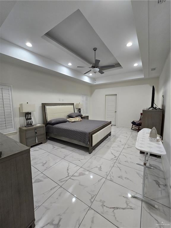 bedroom with ceiling fan and a tray ceiling