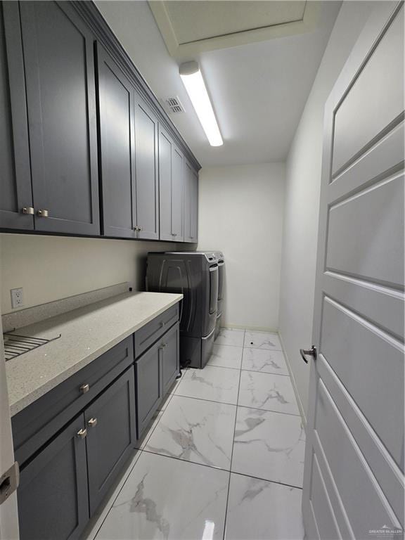 clothes washing area featuring cabinets and washing machine and dryer