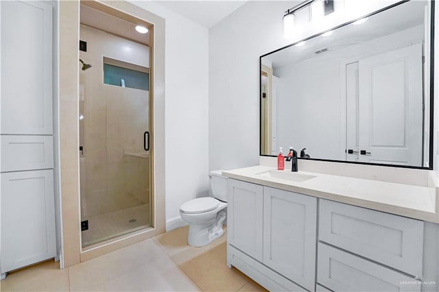 bathroom featuring tile patterned floors, vanity, a shower with shower door, and toilet