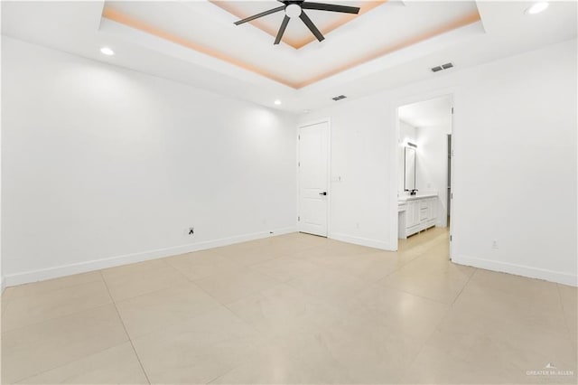 spare room featuring ceiling fan, light tile patterned floors, and a tray ceiling