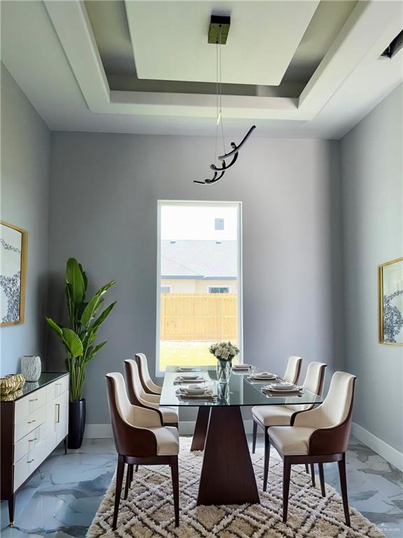 532 Demi St, Edinburg, TX 78542 - dining room with light marble finish floors, a tray ceiling, and baseboards