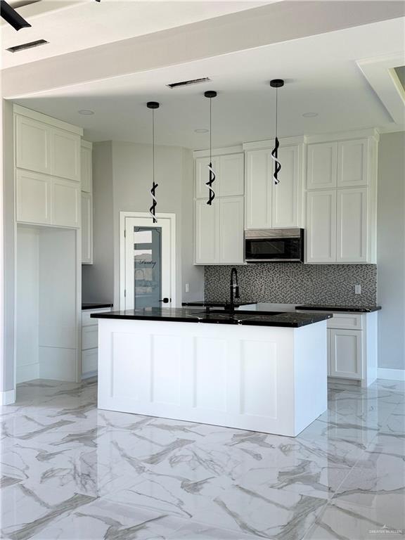532 Demi St, Edinburg, TX 78542 - kitchen with stainless steel microwave, backsplash, dark countertops, and white cabinets