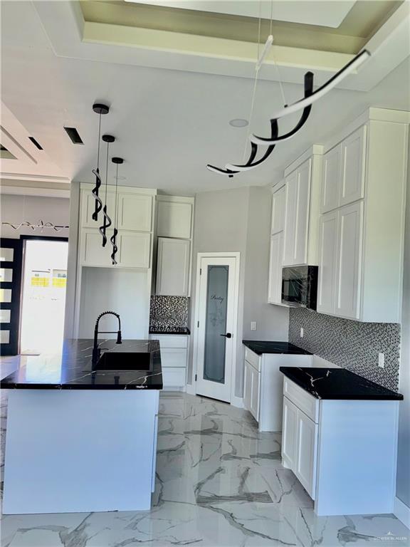 532 Demi St, Edinburg, TX 78542 - kitchen with a sink, black microwave, backsplash, dark countertops, and a kitchen island with sink