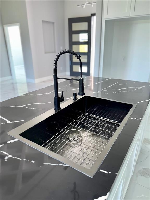 532 Demi St, Edinburg, TX 78542 - kitchen view of a sink, white cabinetry, and baseboards