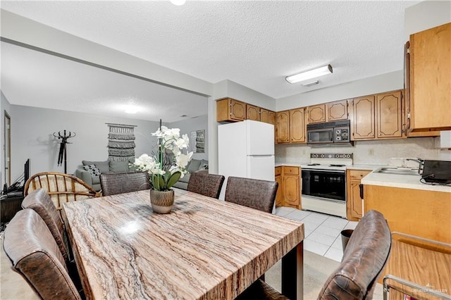 tiled dining room featuring a textured ceiling and sink