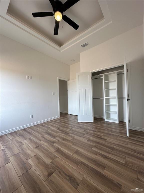 2413 N Woody St, Edinburg, TX 78541 - unfurnished bedroom featuring a tray ceiling, dark wood-style flooring, a closet, ceiling fan, and baseboards