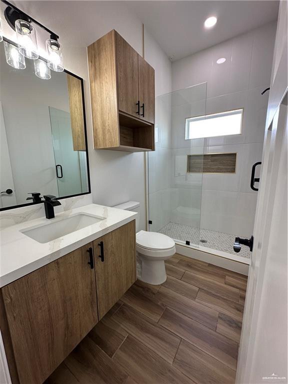2413 N Woody St, Edinburg, TX 78541 - bathroom with a shower stall, toilet, wood finished floors, and vanity