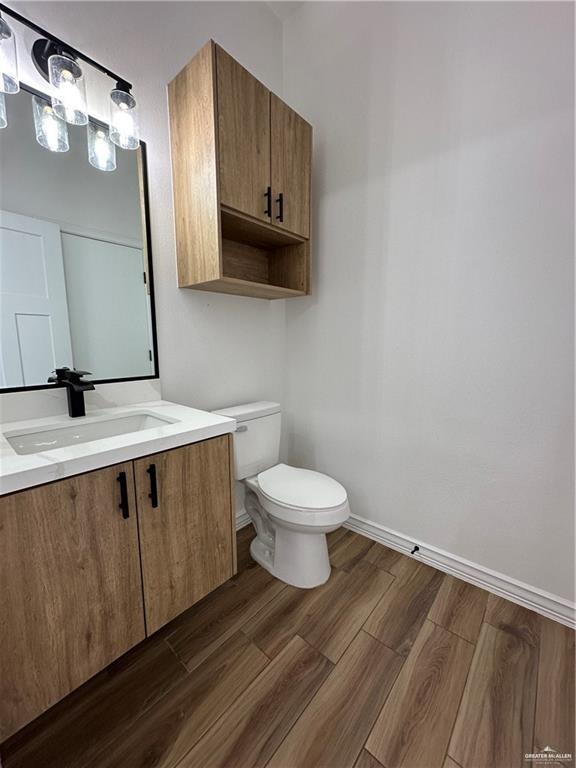 2413 N Woody St, Edinburg, TX 78541 - bathroom with toilet, wood finished floors, baseboards, and vanity