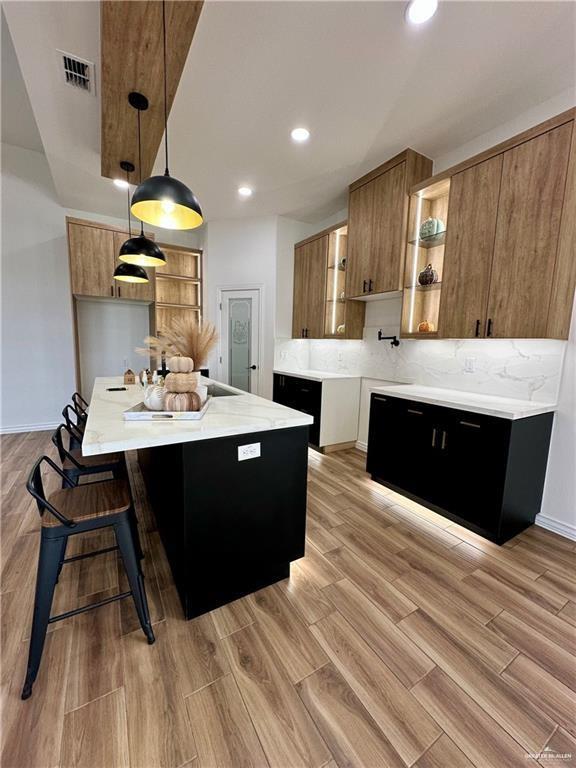 2413 N Woody St, Edinburg, TX 78541 - kitchen featuring open shelves, light countertops, brown cabinetry, tasteful backsplash, and pendant lighting
