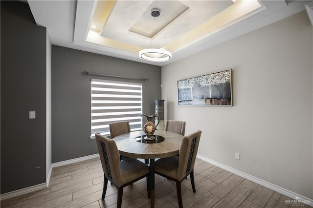 dining space with wood tiled floor, baseboards, and a raised ceiling