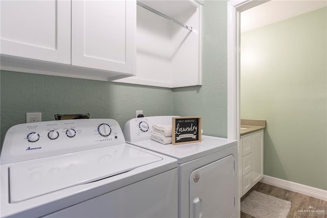 laundry room with washer and clothes dryer, cabinets, and wood-type flooring